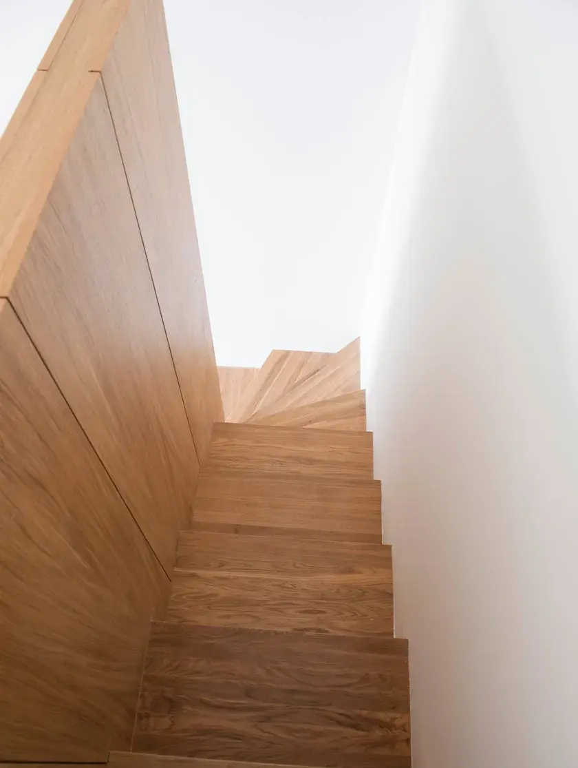 at the top of a winding wood-clad sculptural staircase looking down