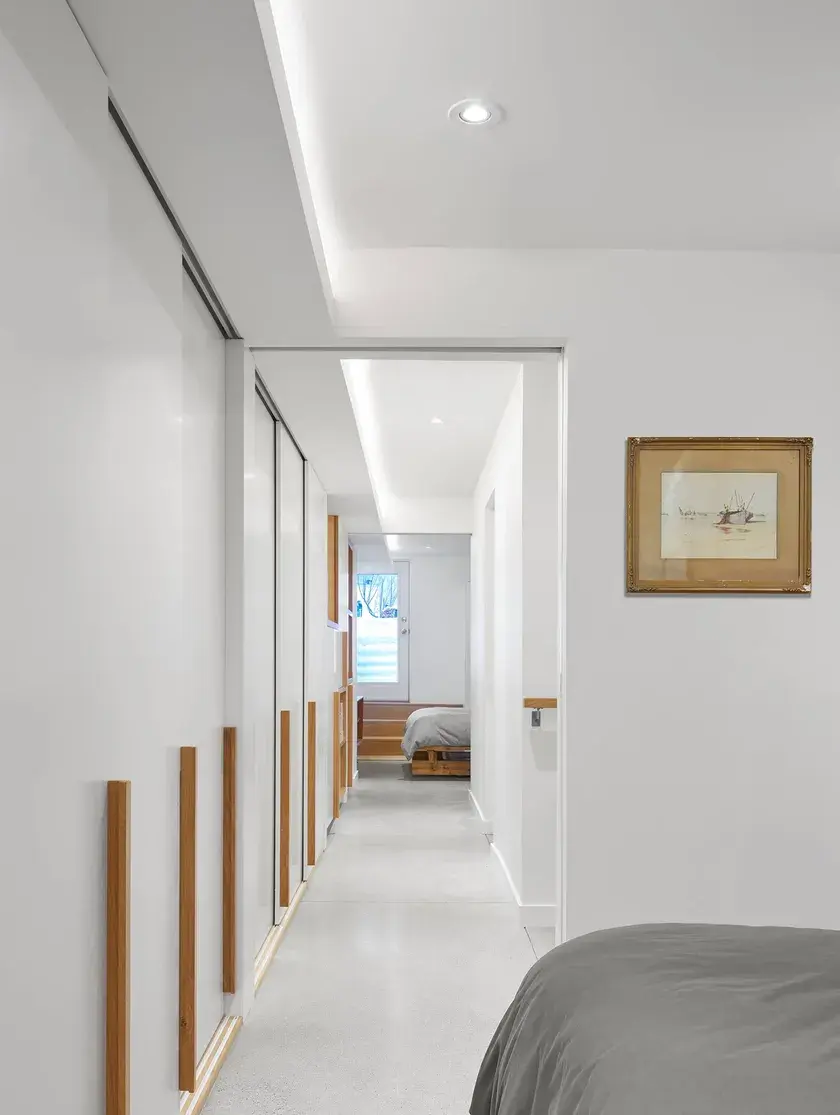 two bedrooms connected by a long narrow hallway with one long continuous millwork wall 