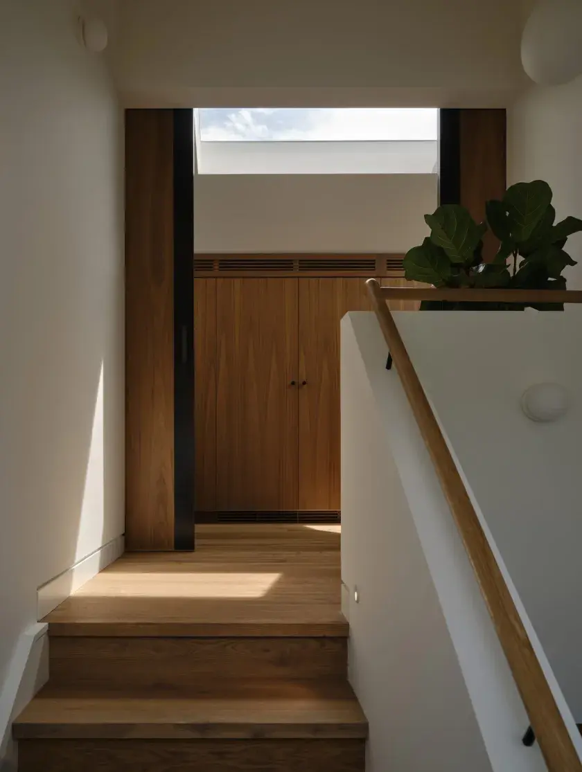 The upper landing of a staircase facing the top white oak steps, and to the back, custom walnut cabinets.