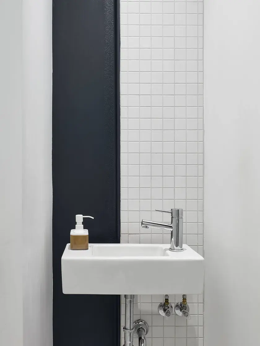 close up of a bathroom sink with white tiles and navy blue panel