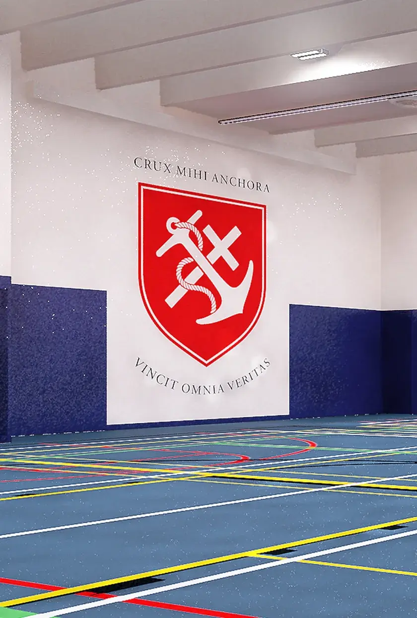 A school gym with a branded wall showing the school crest, an anchor and a cross intersecting inside of a red shield