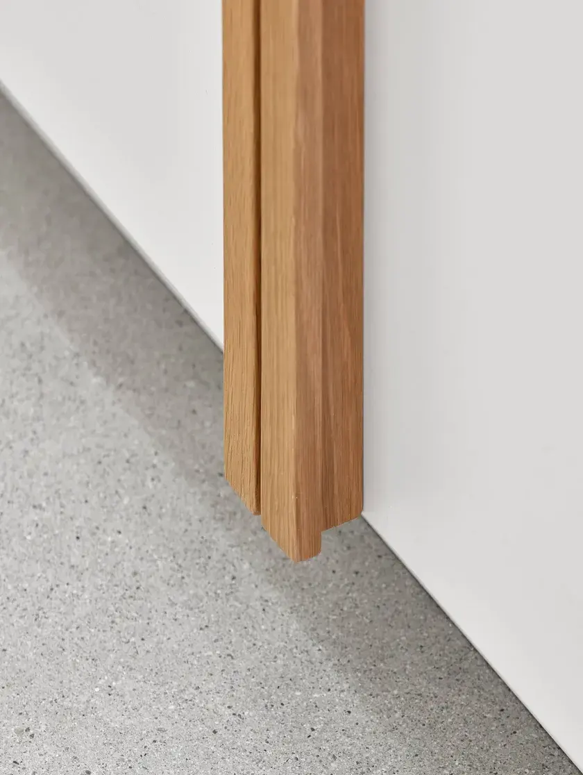 close up of a white millwork wall with solid oak handles, and polished concrete flooring