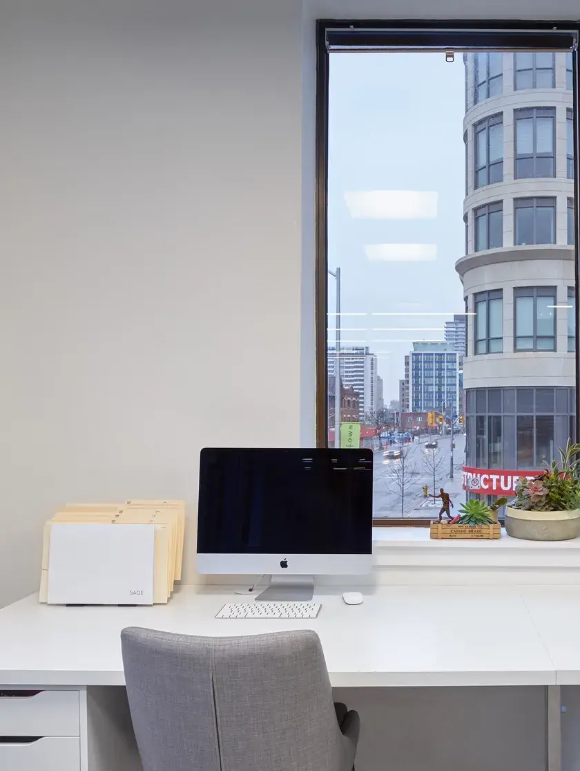 a second floor office space with a desk, chair, and desktop monitor overlooking a main street