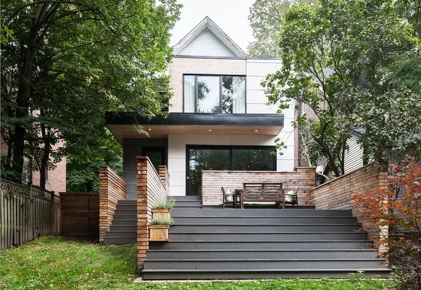 the backyard to a two-storey home, with grey steps leading to a patio