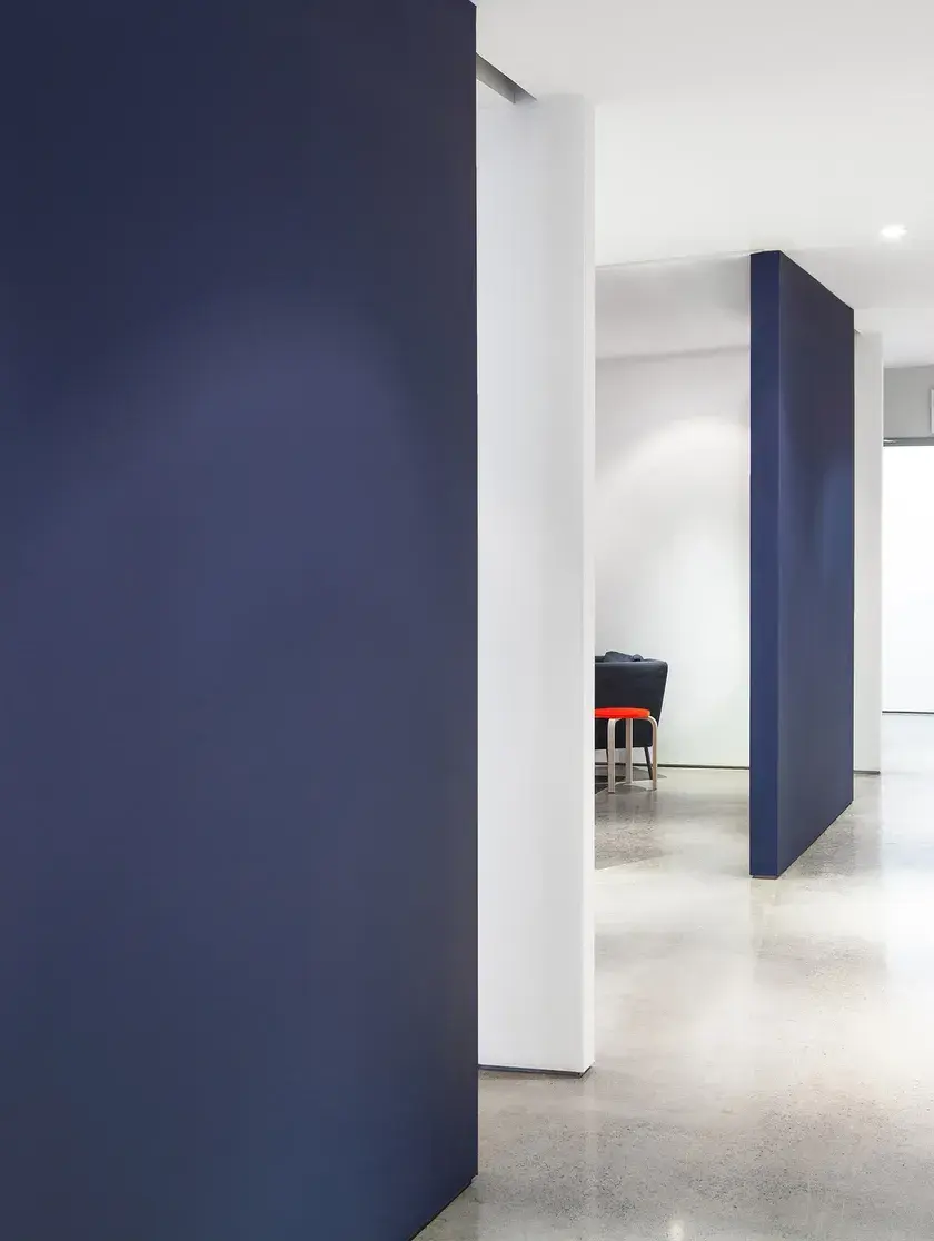 a hallway with two office rooms concrete floors, white walls, and navy blue, floor to ceiling sliding doors